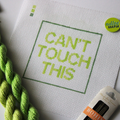 Threaded & Tipsy hand-painted needlepoint canvas featuring the phrase “CAN’T TOUCH THIS” in bold gradient lime and yellow-green block letters, framed by a green rectangular border. A small painted color guide with three green shades appears in the top lef