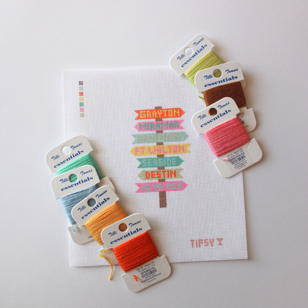 Needlepoint Kit and Canvas with Colorful embroidery thread packages with labels on a white background
