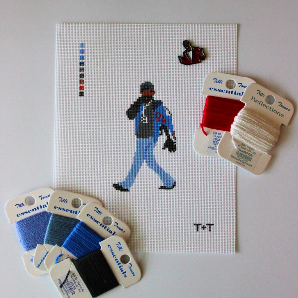 Threaded & Tipsy hand-painted needlepoint canvas featuring a pixel-style figure of a man walking while holding a phone to his ear, dressed in a black cap, black hoodie, blue jeans, and a blue and black jacket with red “RM” lettering. A painted color guide