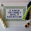 Threaded & Tipsy hand-painted needlepoint canvas featuring the phrase “IT RAN IN THE FAMILY UNTIL IT RAN INTO ME” in bold navy blue block letters. The quote is framed by a navy and lime green geometric border. Surrounding the canvas are twisted skeins of 