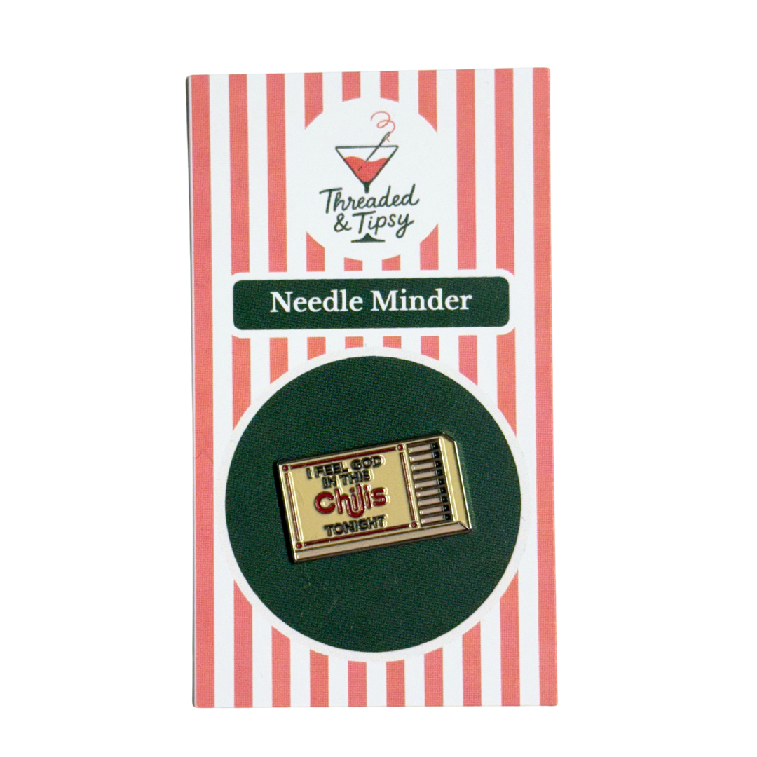 Gold matchbox-shaped needle minder on striped packaging with 'Threaded & Tipsy' branding.